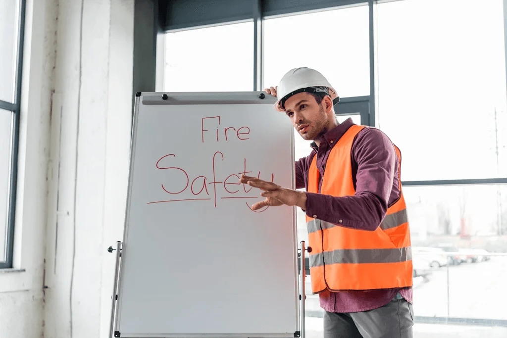 man holding a board with fire safety written on it